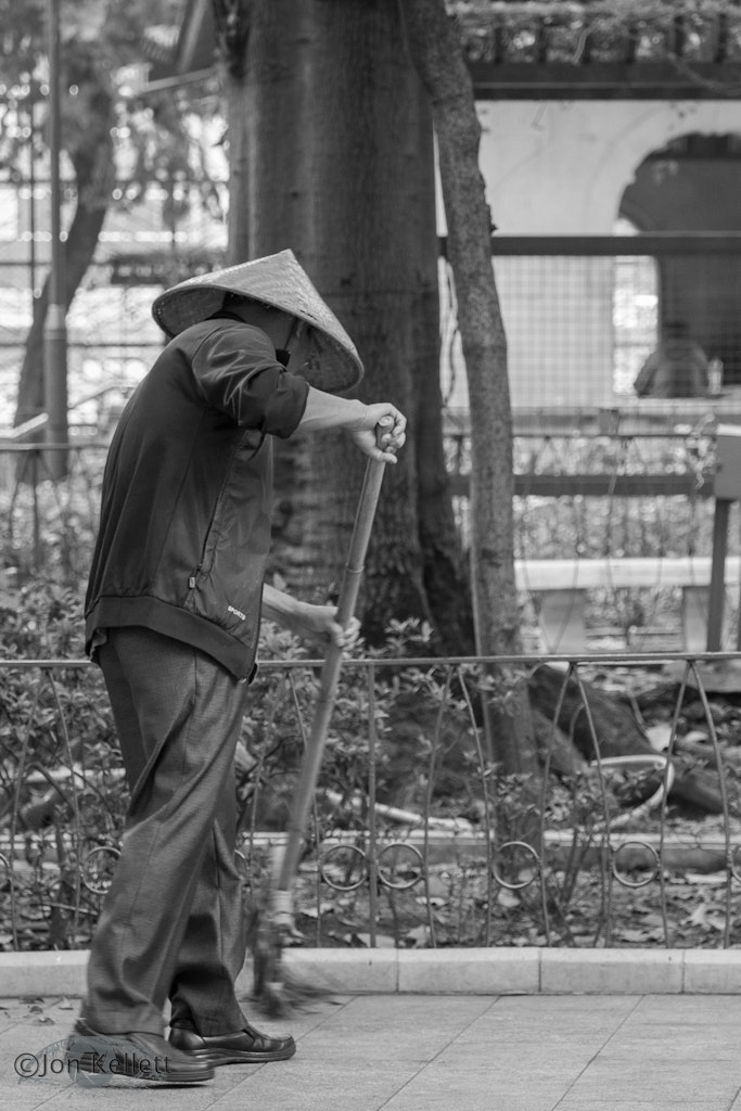 Cleaner in Jordan - A cleaner at work as patrons enjoy the peace or practice Tai Chi. The traditional broom and hat still commonly used by older residents.