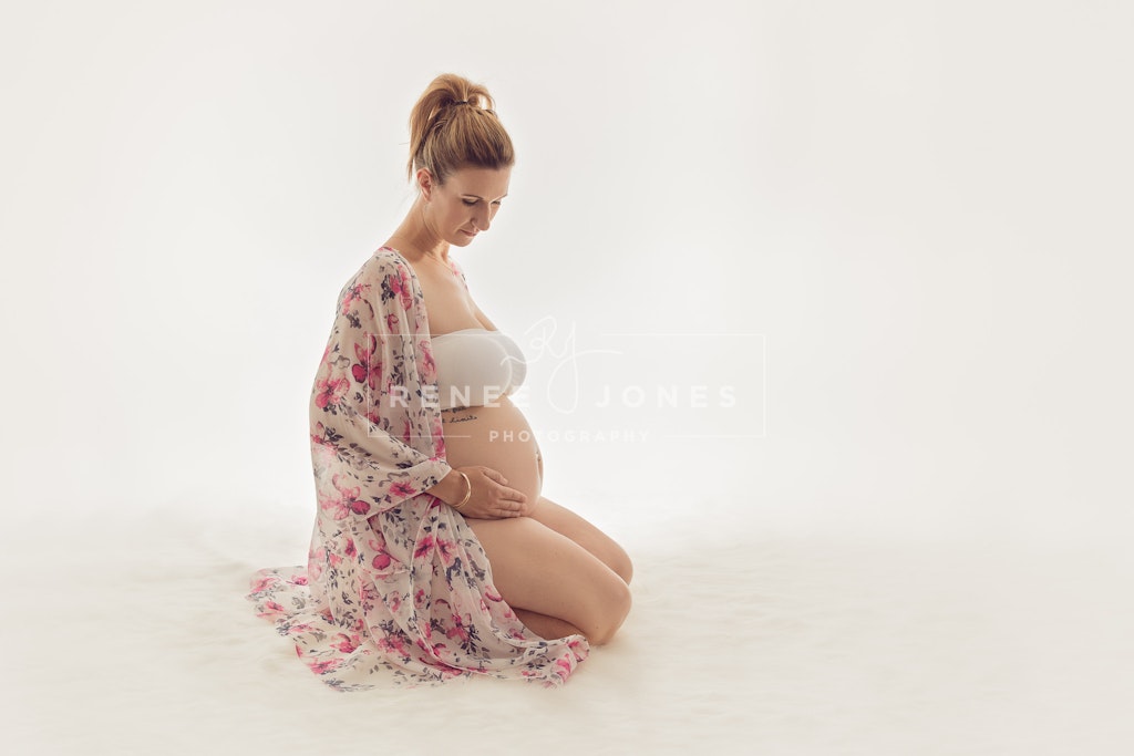 Sitting mum to be - Expecting mum in a floral drape sitting on her knees showing her baby bump.